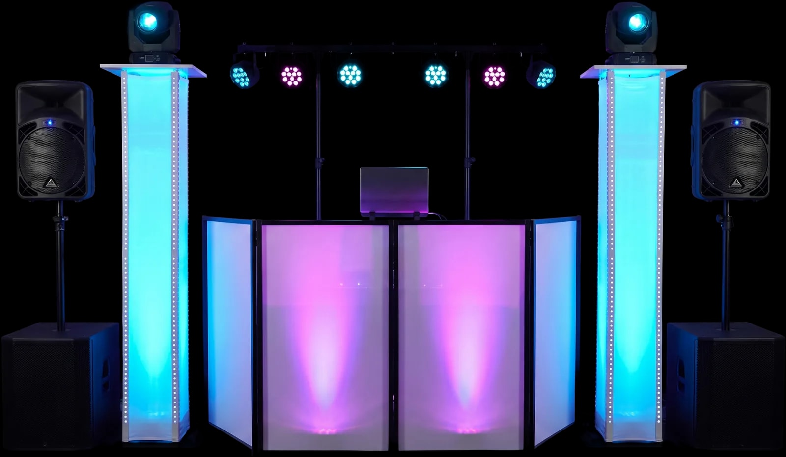 La cabine de DJ N'RICO installée sur scène : deux colonnes lumineuses LED cyan encadrent la façade blanche rétroéclairée en magenta, avec deux enceintes sur pieds et une rampe de projecteurs LED au-dessus, dans une salle sombre.